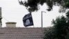 FILE - An Islamic State flag flies over the customs office of Syria's Jarablus border gate, Aug. 1, 2015. A Maryland man has been detained on federal charges in connection with the IS group.