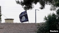 FILE - An Islamic State flag flies over the customs office of Syria's Jarablus border gate, Aug. 1, 2015. A Maryland man has been detained on federal charges in connection with the IS group.