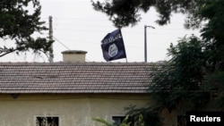 ARSIP - Sebuah bendera Islamic State berkibar di kantor pabean gerbang perbatasan Jarablus di Suriah sebagaimana tampak dari kota Karkamis, provinsi Gaziantep, Turki, 1 Agustus 2015 (foto: Reuters/Murad Sezer)