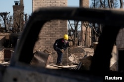 Anggota tim SAR mencari puing rumah yang hangus akibat Kebakaran Palisades di Pacific Palisades, Los Angeles, California, 14 Januari 2025. (Foto: David Ryder/Reuters)