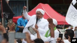 FILE - Hardline Islamic cleric Rizieq Shihab, center, speaks to a group of his followers in Jakarta, Indonesia, Nov. 10, 2020.