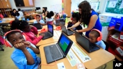 Second grade student Khalil Morgan, left, reacts after completing an interactive math problem on his computer, with teacher Jillian Martin, standing to the right, at Turner Elementary School in southeast Washington, Tuesday, Aug. 29, 2017. (AP Photo/Manuel Balce Ceneta)