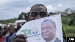 FILE—A supporter of Congolese doctor and presidential candidate Denis Mukwege holds a campaign poster at Kavumu-Bukavu airport, as Mukwege arrives for a campaign rally in Bukavu, capital of South Kivu province, eastern Democratic Republic of Congo, on November 25, 2023.