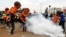 Protesters carrying giant baby models run away after riot police fired tear gas to disperse them during a march dubbed "Kenya ni Kwetu" in Kenya's capital Nairobi, Feb. 13, 2014. 