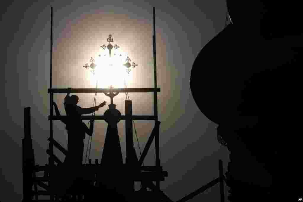 Workers prepare for the restoration of a cross on the Church of the Life-Giving Trinity in Ostankino, a monument of old Russian cult architecture, during a sunset in Moscow, Russia, Aug. 5, 2020.