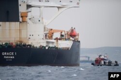 (FILES) In this file photo taken on July 06, 2019 A ship approaches supertanker Grace 1 off the coast of Gibraltar on July 6, 2019. Gibraltar police have arrested the Indian captain and chief officer of a seized Iranian tanker suspected of breaching…