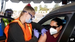 FILE - A teacher at Grant Elementary School in Hollywood receives a shot of the Moderna COVID-19 vaccine from a nurse at a site for employees of the Los Angeles school district in the parking lot in Inglewood, Calif., March 2, 2021.