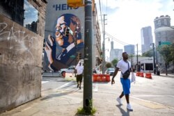 Un mural en Atlanta Georgia, muestra un retrato del fallecido legislador y pionero de los derechos civiles, John Lewis, abajo del cual las personas han colocado flores y recuerdos. Sábado 18 de julio de 2020.