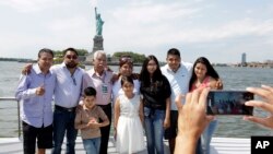 Luis Mendez Chanes, third left, poses with his daughter Marta Mendez, fourth left, as they reunite after 24 years in front of the Statue of Liberty aboard the Bateaux New York boat, July 5, 2017, in New York.