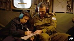 A handout photo provided by the IDF on Nov. 27, 2023, showing Gal Goldstein Almog, an 11-year-old Israeli hostage that was released by Hamas, writing on a board as he returns to the Middle Eastern nation in an IAF helicopter.