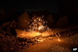 Un niño palestino juega con fuegos artificiales mientras celebra el inicio del mes sagrado musulmán del Ramadán junto a una mezquita destruida por los ataques aéreos israelíes en Rafah, Franja de Gaza, el domingo 10 de marzo de 2024. (Foto AP/Fatima Shbair)