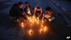 Iraqi journalists light candles where, according to police, a Kurdish officer of the Iraqi president's guard shot dead the bureau chief of a local radio station in Baghdad, March 22, 2014.