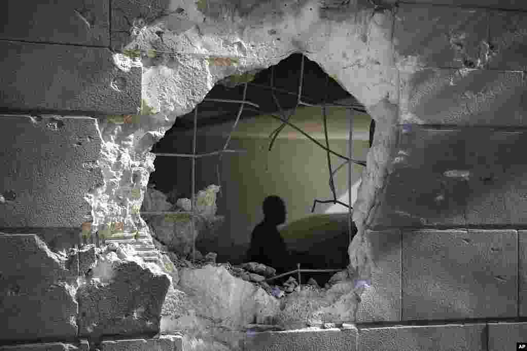 A man is seen trough a hole in a wall of a residential building after it was struck by a rocket fired from the Gaza Strip in Ashkelon, Israel.