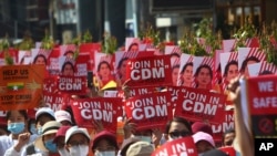 Anti-coup protesters hold up signs calling on others to join the CDM (Civil Disobedience Movement) during a rally near the Mandalay Railway Station in Mandalay, Myanmar, Feb. 22, 2021.