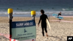 A sign tells surfers to leave once they have finished surfing at Bondi Beach in Sydney, Tuesday, April 28, 2020, as coronavirus pandemic restrictions are eased. The beach is open to swimmers and surfers to exercise only. (AP Photo/Rick Rycroft)