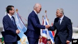 El presidente de EEUU, Joe Biden, saluda al primer ministro israelí, Yair Lapid, a la derecha, junto al presidente israelí, Isaac Herzog, a su llegada a Tel Aviv el 13 de julio de 2022.