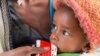 FILE - A child held by his mother eats emergency food after being screened for malnutrition in Debub Health Centre in Wajirat woreda in Southern Tigray in Ethiopia, July 19, 2021.