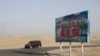 资料照片：新疆和田沙漠公路展示的“和田市团结新村欢迎您！”的标牌。(2018年9月21日)