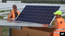 FILE - Workers install solar panels at the Constantine photovoltaic power station in Cestas, near Bordeaux, southwestern France.