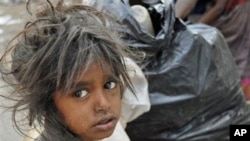 A child sits in front of a garbage dump on World Poverty Day in Hyderabad, India, 17 October 2007 (FILE).