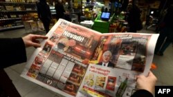 A woman reads the "Blesk" Czech tabloid newspaper with images of the Czech Republic's Minister of Health Roman Prymula attending a meeting at a restaurant despite recent coronavirus restrictions, in Prague, Oct. 23, 2020.