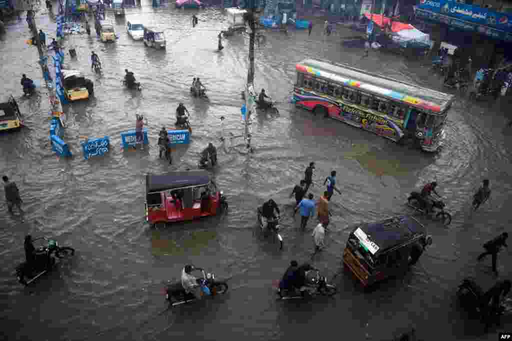 Commuters make their way along a flooded street after heavy monsoon rains in Pakistan's port city of Karachi, Pakistan.