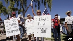 Judy Schulz, center, cheers as her husband Richard Schulz, left, both of Glendale, Ariz., joined hundreds supporting Arizona's new law on illegal immigration as they listen to speakers near the capital in Phoenix. The law was later largely blocked by a fe