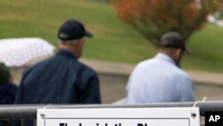 State workers walk away after attaching a sign announcing a new curfew to a fence near the state Capitol in Nashville, Tennessee, Oct. 27, 2011