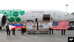 FILE - In this photo released by the National Task Force Against COVID19, US officials hold a U.S. flag as Philippine officials hold the Philippine flag beside boxes containing Johnson & Johnson vaccines as they arrive in Manila, July 16, 2021., J