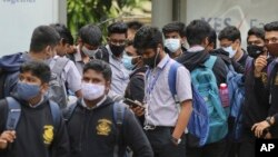 ভারতের বেঙ্গালুরুতে স্কুলে যাবার জন্য শিক্ষার্থীরা মাস্ক পরে একটি বাস স্টপে অপেক্ষা করছে। নভেম্বর ৩০, ২০২১। 