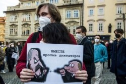 Protesters embrace while holding a poster depicting Russian President Vladimir Putin and Belarussian President Alexander Lukashenko during a demonstration in support of Russian opposition leader Alexei Navalny in Prague on April 2.