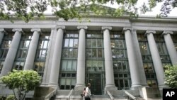 FILE - A bicyclist walks by Harvard University's Langdell Hall, which includes Harvard Law School's library, in Cambridge, Massachusetts, Aug. 1, 2005.