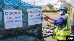 FILE - A worker handles boxes of COVID-19 vaccines, delivered as part of the COVAX equitable vaccince distribution program, at Ivato International Airport, in Antananarivo, Madagascar, May 8, 2021. 