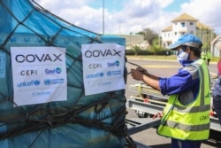 FILE - A worker handles boxes of COVID-19 vaccines, delivered as part of the COVAX equitable vaccince distribution program, at Ivato International Airport, in Antananarivo, Madagascar, May 8, 2021.