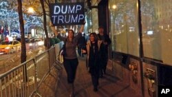 Unas manifestantes protestan por la presencia de Donald Trump en el probrama Saturday Night Live, con un letrero que dice "Boten a Trump".