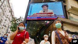 FILE - A TV screen broadcasts Hong Kong Chief Executive Carrie Lam during a news conference in Hong Kong, March 30, 2021. 