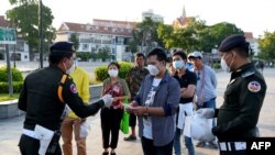 FILE PHOTO - Military police officers hand out free face masks to people, amid concerns over a spread of the Covid-19 coronavirus at a park in Phnom Penh on November 12, 2020. (Photo by TANG CHHIN Sothy/AFP)