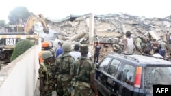 People look at an excavator clearing the rubble on the scene of a six-story shopping center that collapsed in Accra, November 7, 2012.