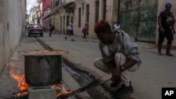 Un hombre cocina sopa sobre un fogón en una acera, durante un apagón en La Habana, Cuba, el miércoles 4 de diciembre de 2024.