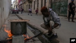 ARCHIVO - Un hombre cocina una sopa en un fuego en la acera, durante un apagón en La Habana, Cuba, el 4 de diciembre de 2024. 