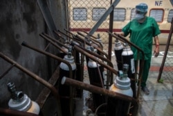 A health worker checks oxygen cylinders stored next to a train at a railway station in Gauhati, India, May 6, 2021.