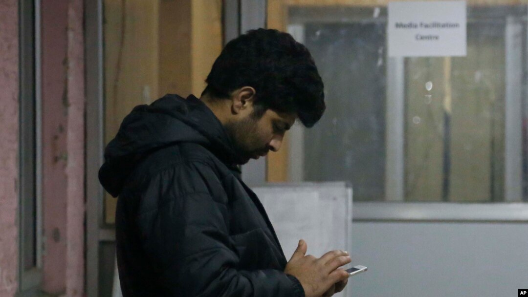 Seorang pria tengah memeriksa tteleponnya di kawasan Srinagar, Kashmir yang dikontrol India, 31 Desember 2019. 