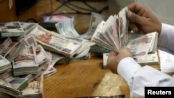 FILE - An employee counts money at a bank in Cairo, Egypt, Sept. 4, 2014. 