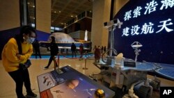 资料照片：2021年3月12日，一名参观者在北京观看中国天问一号飞船火星探测器复制品的展览。（美联社照片）
