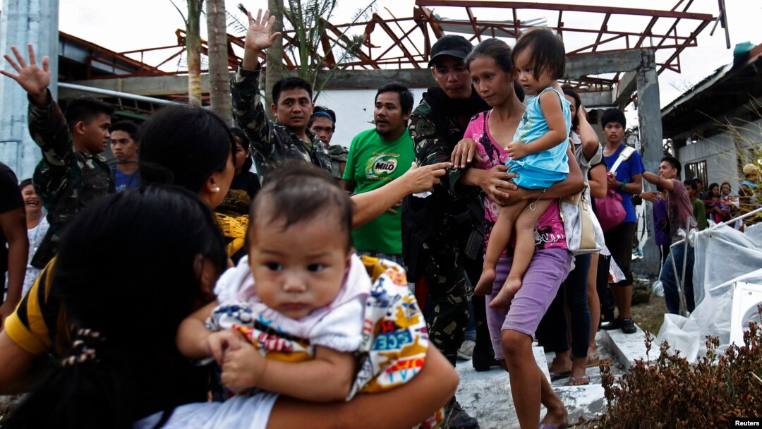 Soldiers help residents as they board a U.S. military C130 aircraft to leave for Manila after Typhoon Haiyan battered Tacloban in central Philippines, Nov. 11, 2013.