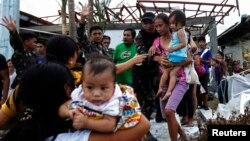 Soldiers help residents as they board a U.S. military C130 aircraft to leave for Manila after Typhoon Haiyan battered Tacloban in central Philippines, Nov. 11, 2013.