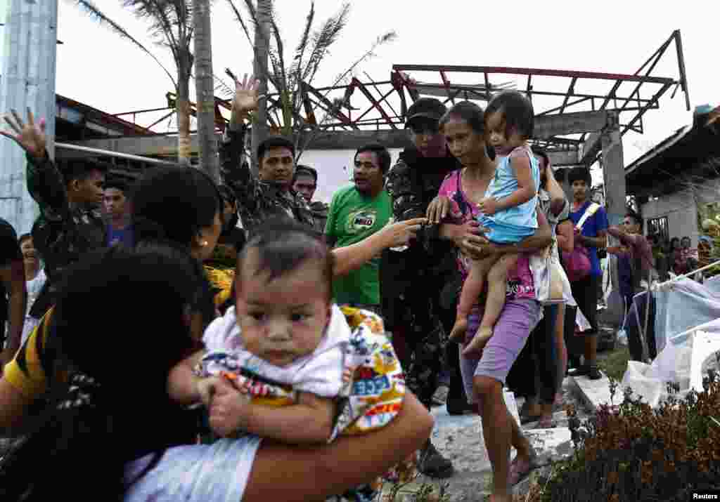 Tentara membantu warga naik pesawat militer AS C130 yang akan membawa mereka ke Manila, menyusul topan Haiyan yang menghantam kota Tacloban di Filipina tengah (11/11). (Reuters/Edgar Su)