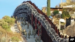 Fotografía del sábado 2 de febrero de 2019 de soldados de la Armada de Estados Unidos colocando alambre de púas adicional en una cerca en la calle Nelson en el centro de Nogales, Arizona.