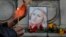 A woman holds a candle next to a portrait of slain television reporter Viktoria Marinova during a vigil at the Liberty Monument in Ruse, Bulgaria, Oct. 8, 2018.