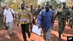 A Friday, Jan. 16, 2015 photo released by the Uganda People's Defence Force (UPDF), shows a man said by the UPDF to be the wanted Lord's Resistance Army (LRA) commander Dominic Ongwen, center-right, is handed over by the UPDF to the African Union Regional Task Force who later handed him over to Central African Republic authorities, in the Central African Republic, Jan. 16, 2015. 